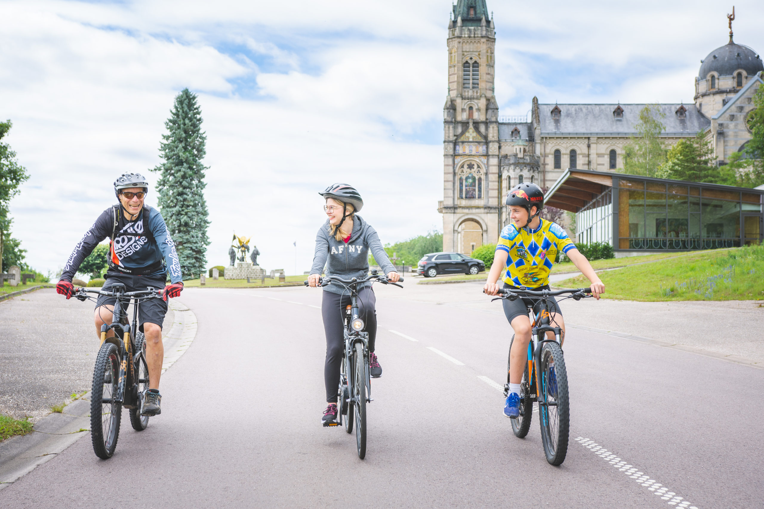 Des cyclistes en rando devant la basilique de Domrémy-la-Pucelle.