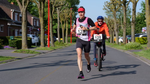 Benjamin Polin en train de courir, accompagné par son frère en vélo, derrière lui.