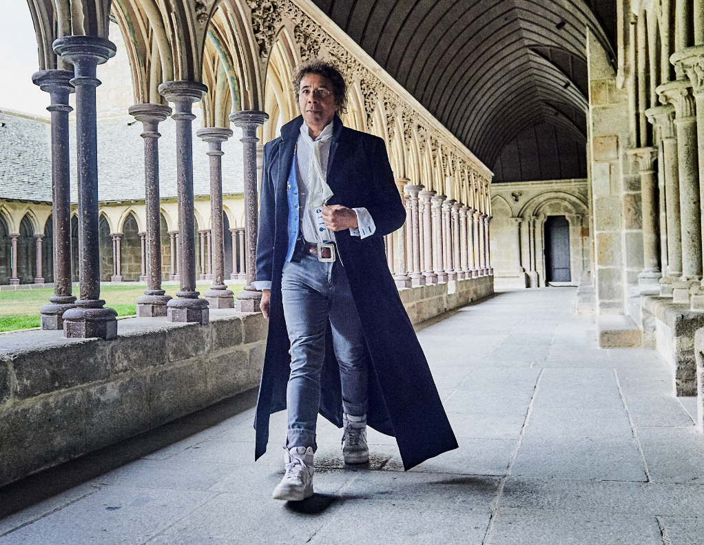 Laurent Voulzy marche dans la cour d'une église.