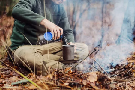 hunter pours water from a bottle into a metal mug.