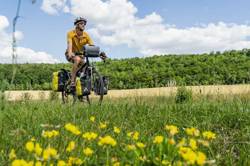 Un cycliste sur le long d'une route, à coté d'un champ de fleurs