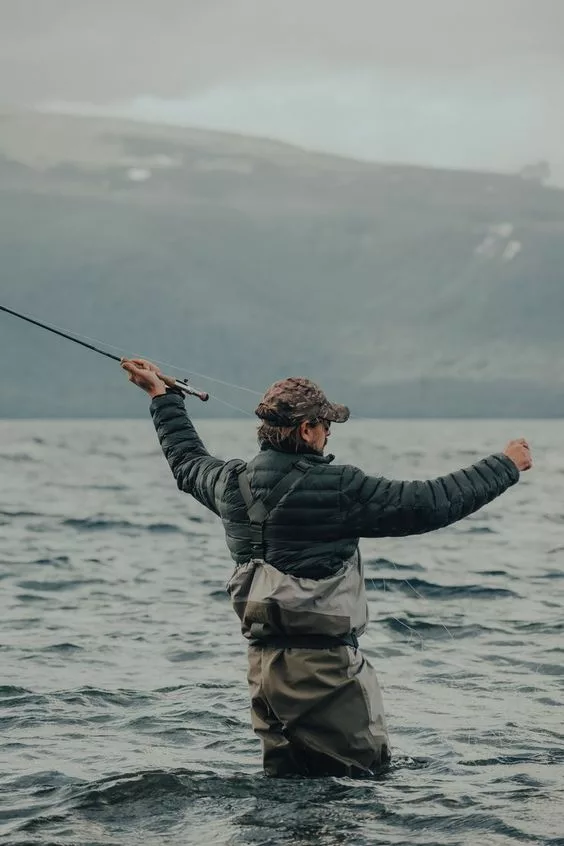 Un pêcheur à la mouche en waders, dans un lac.
