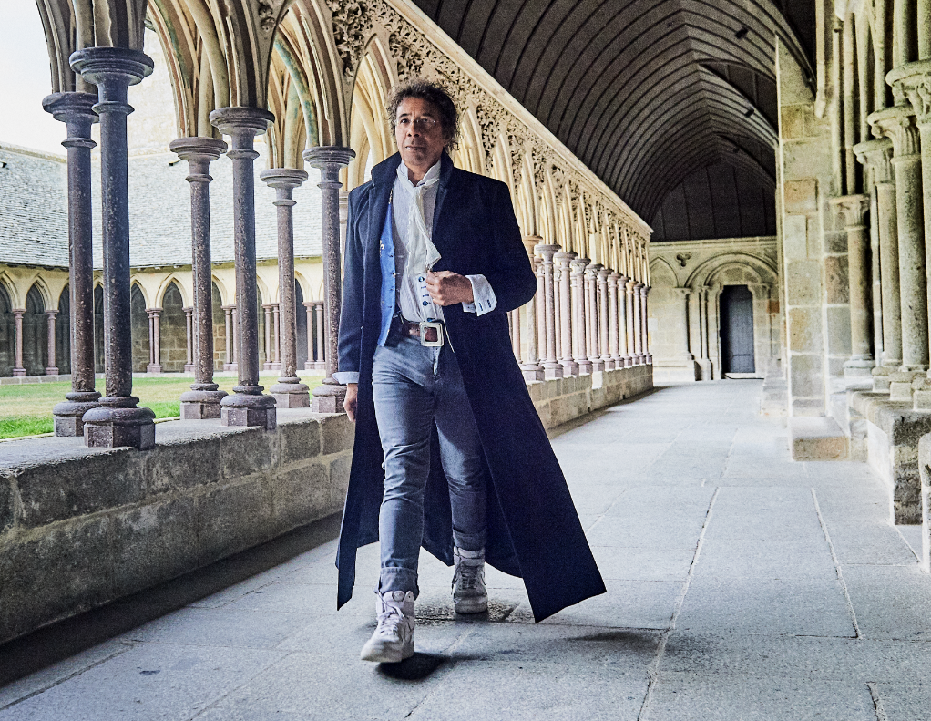 Laurent Voulzy : le mystique rêveur en concert exceptionnel dans la Cathédrale de Saint-Dié-des-Vosges 5• 100% Vosges Laurent Voulzy marche dans la cour d'une église.